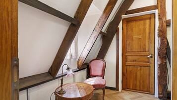 Une pièce avec une porte en bois, une chaise et une table sur laquelle se trouve une lampe.