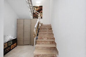 Un escalier avec une rampe, un tableau accroché au mur et une cloison en osier.