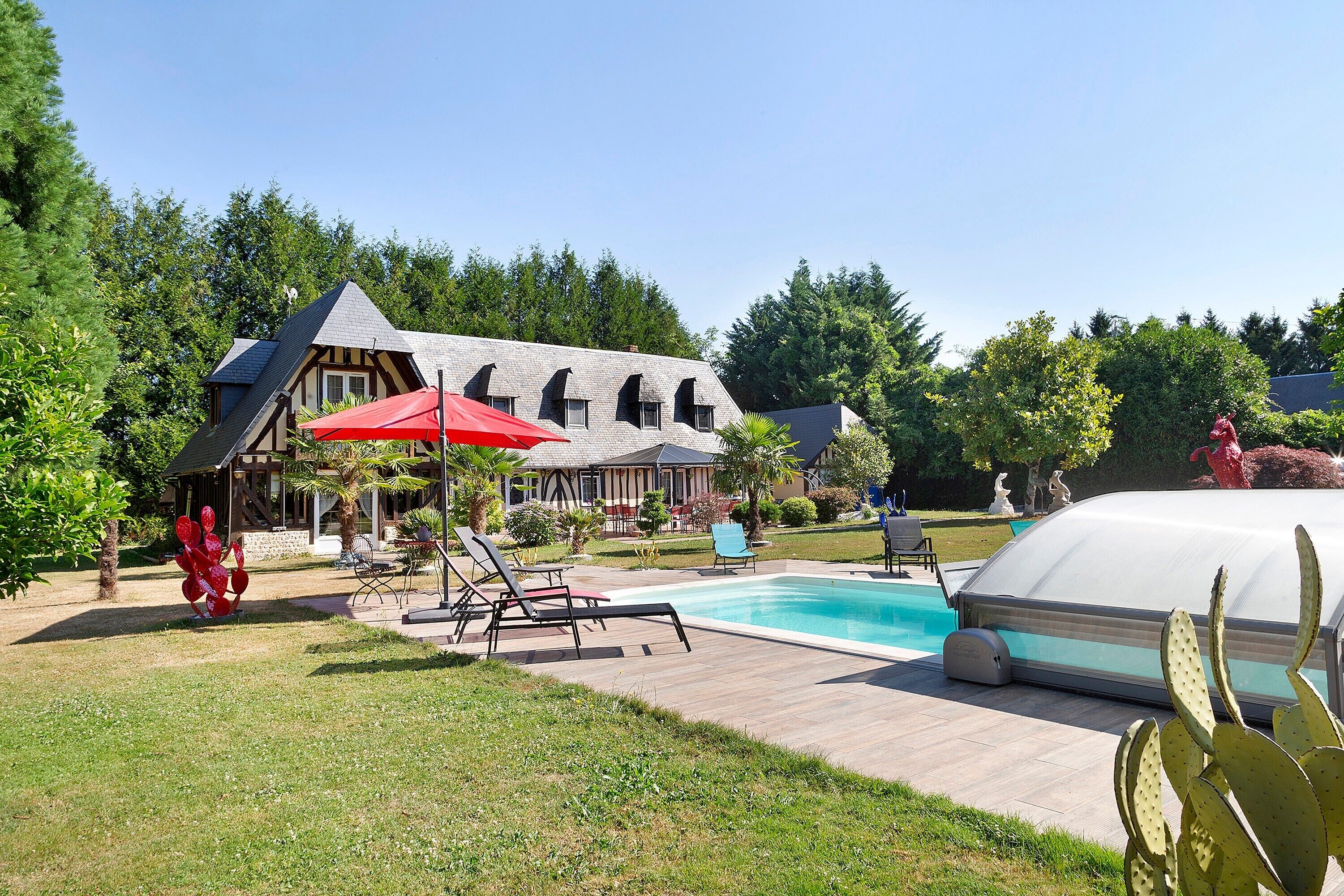 Una casa con piscina, bañera de hidromasaje techada y un paraguas rojo.