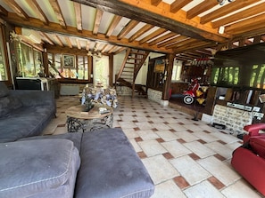 A rustic interior with a checkered floor, wooden beams, a sofa, a table with a statue, and a red toy car.