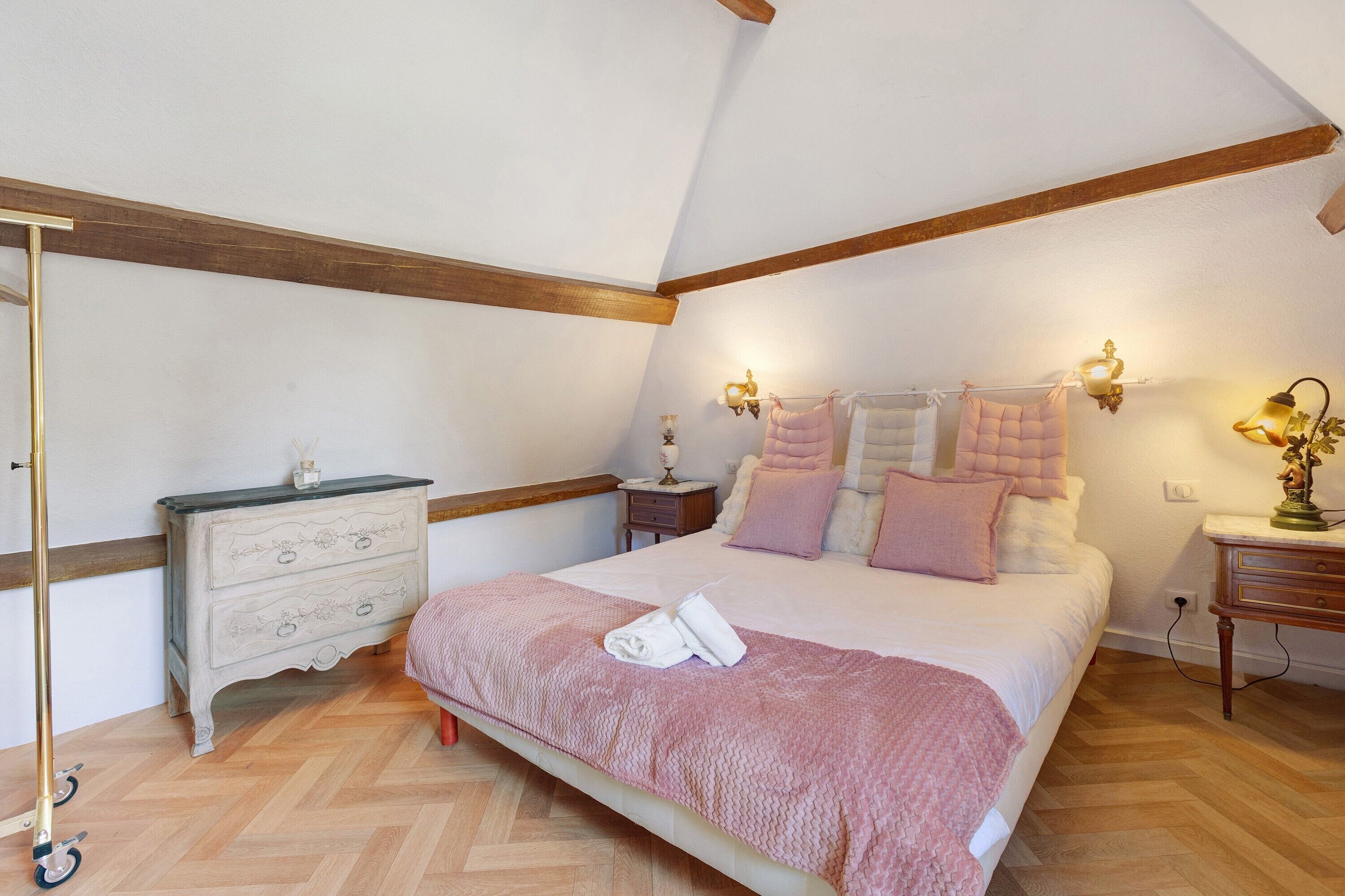 Une chambre à coucher avec un lit, des tables de chevet, une commode et une lampe.
