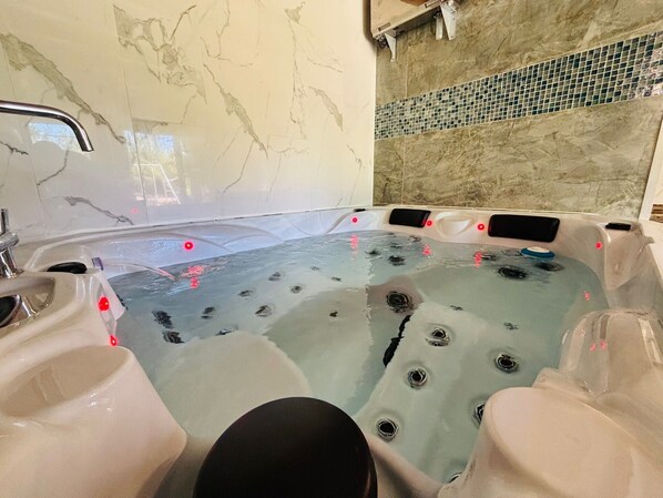 A hot tub with jets, a marble wall, and a tiled backsplash.