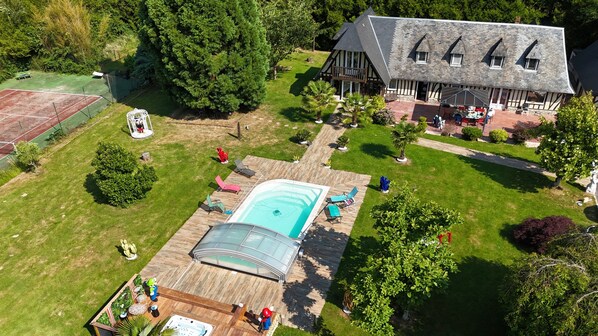Una casa grande con piscina, cancha de tenis y un jardín bien cuidado.