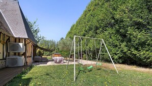 A house with a wooden deck, a swing set, and a lawn with dandelions. - Normandy House: Spa, Pool, Jacuzzi, Tennis, 4 Bedrooms, 12 Guests (Lieurey)