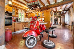 A kitchen with a vintage red scooter, wooden cabinets, and a gas cylinder. - Normandy House: Spa, Pool, Jacuzzi, Tennis, 4 Bedrooms, 12 Guests (Lieurey)