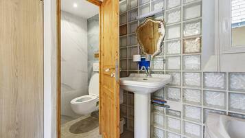 A bathroom with a wooden door, a white sink, a mirror, and a toilet.