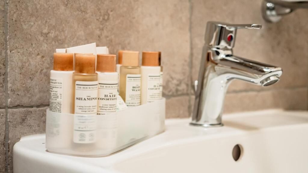 Un lavabo de salle de bain avec un robinet chromé et un porte-bouteilles contenant divers produits de soins capillaires.