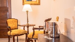 A wooden table with two chairs, a lamp, a bottle of champagne, and two wine glasses. - Palazzo dei Pavoni Relais di Charme (L'Aquila)