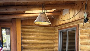 A log cabin interior with a gray sectional sofa, an American flag, and a hanging lamp.