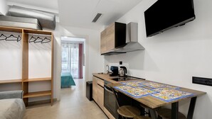 A modern kitchen with a wooden table, bar stools, a built-in oven, and a TV mounted on the wall. - Apartment 'Mini - P1' with Balcony, Wi-Fi and Air Conditioning (Balestrate)