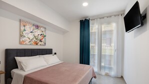 Una camera da letto con un letto, un quadro, una televisione e una finestra con tende.