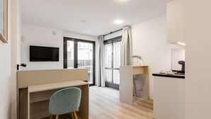 A modern, well-lit room with a desk, chair, and a television mounted on the wall. - Square Rooms by Charming (Madrid)