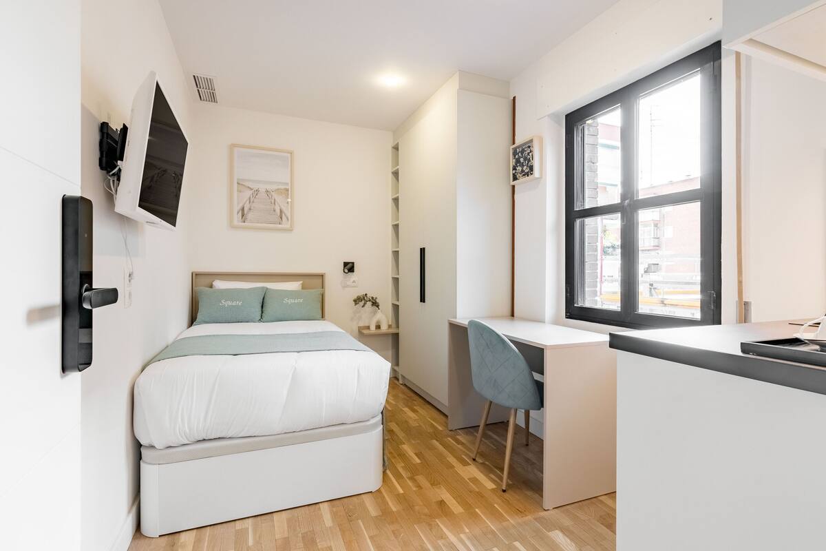 A compact room with a bed, a desk, and a chair.