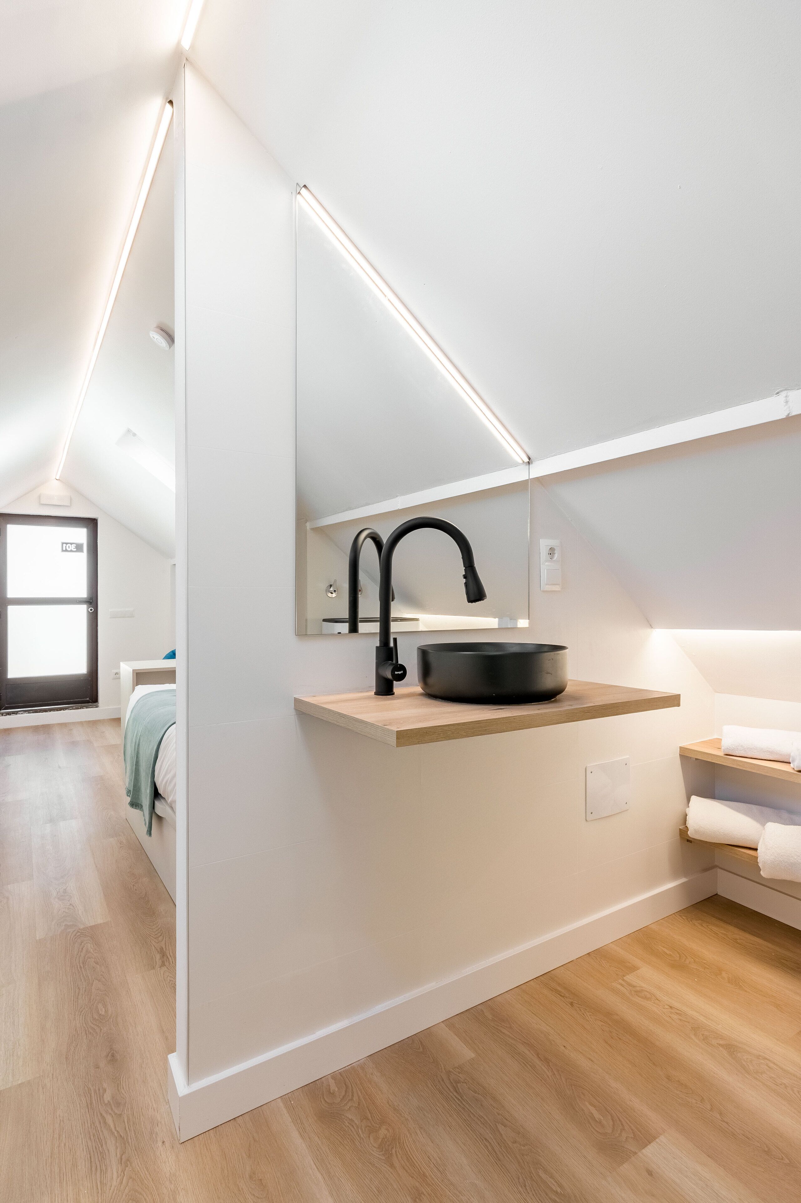 Un baño moderno con un lavabo negro, encimera de madera y un espejo.