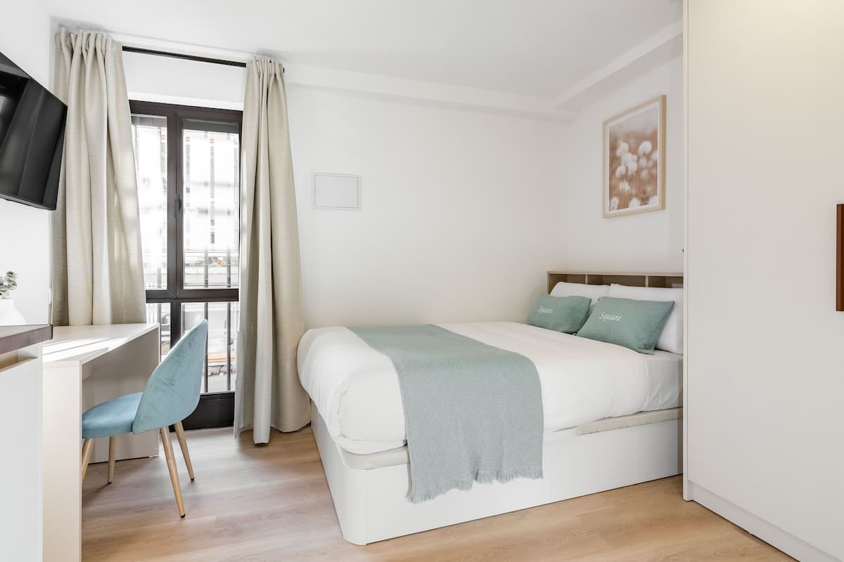 A bedroom with a bed, a desk, and a chair.