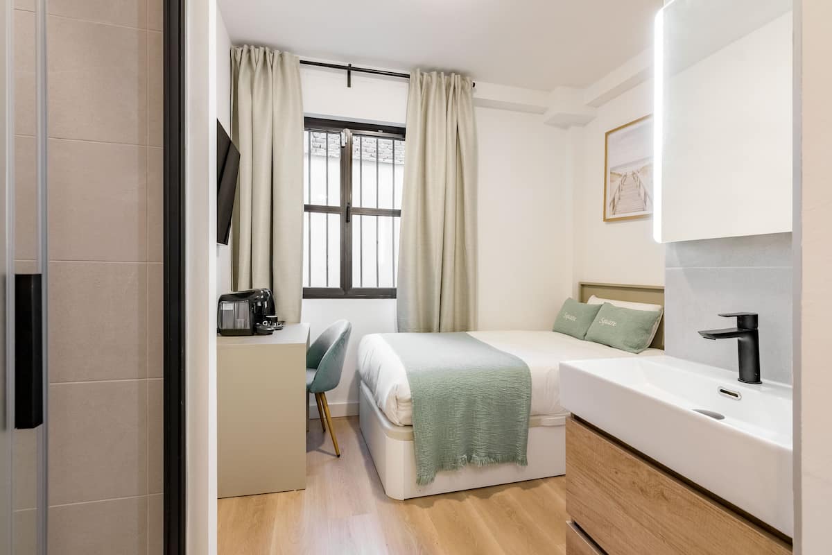 A modern bedroom with a bed, bedside table, and a window with curtains.