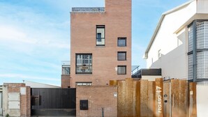 A multi-story building with a brick facade, a gated entrance, and a clear sky. - Square Rooms by Charming (Madrid)