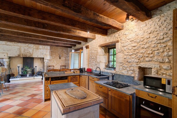 Una cocina rústica con paredes de piedra, vigas de madera y piso de baldosas.