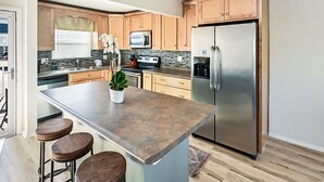 Una cocina moderna con una isla central, armarios de madera, electrodomésticos de acero inoxidable y una planta en maceta.