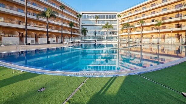A hotel with a swimming pool, multiple balconies, and palm trees. - Apartment 'Para íso do Atlântico' with Shared Pool, Garden, and Wi-Fi (Albufeira)