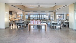 A spacious dining area with a long table and multiple chairs, large windows with a view, and a modern interior design. - Apartment 'Paraíso do Atlântico' with Shared Pool, Garden, and Wi-Fi (Albufeira)