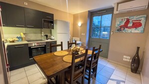 Een kleine keuken met moderne apparaten, een eettafel met placematen, en een raam met uitzicht op bomen.