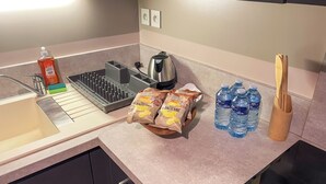 Een keukenblad met een waterkoker, een fles afwasmiddel, een spons en zakken met lekkernijen.
