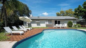Une piscine avec des chaises longues et un espace patio.