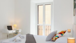 A hotel room with a bed, a desk with a laptop, a window with a view, and a bedside lamp. - Rental in Rome Cesare Apartment (Rome)
