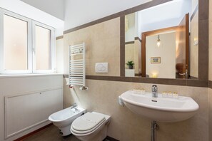 Un baño con inodoro, bidé, lavabo y espejo.