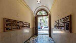 A hallway with tiled flooring, wooden display cases, and an arched doorway leading outside. - Rental in Rome Cesare Apartment (Rome)