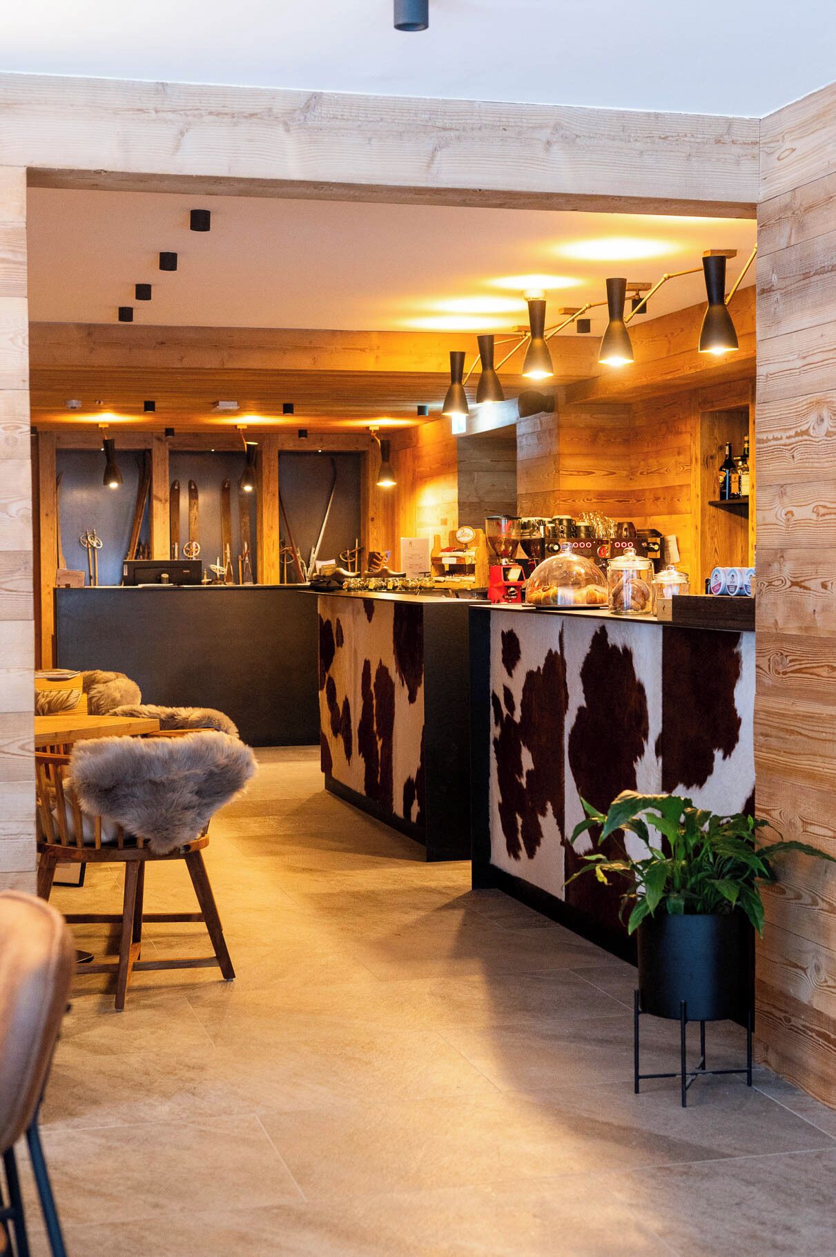 Un área de bar acogedora con detalles de madera, una barra de cuero de vaca y equipo de esquí al fondo.
