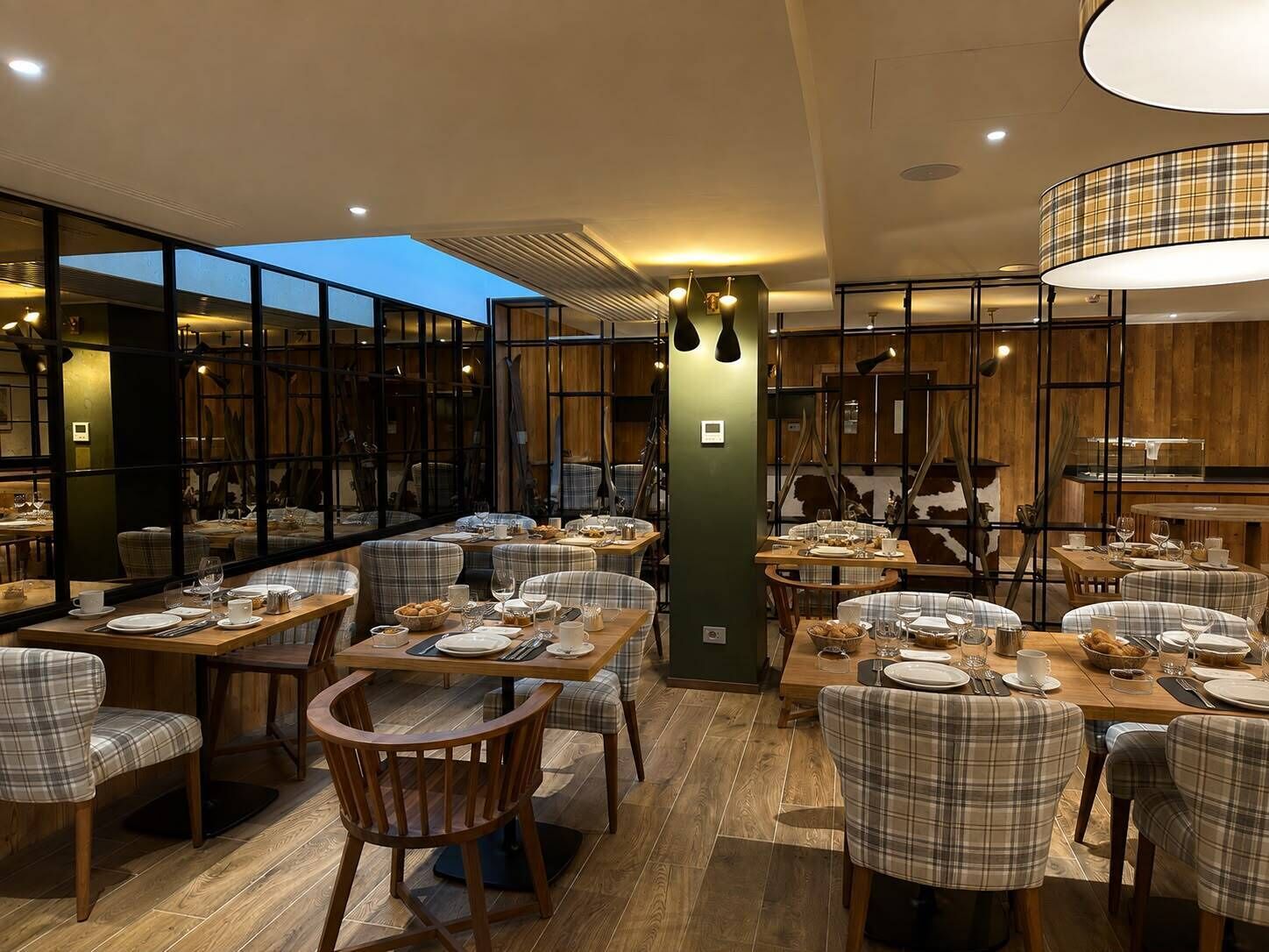 A restaurant with multiple tables and chairs, wooden flooring, and a modern interior design.