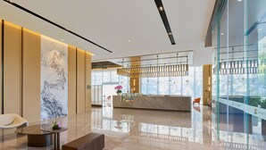 A modern hotel lobby with a marble reception desk, seating area, and large windows offering views. - Hyatt Place Shenzhen Longgang (Shenzhen)