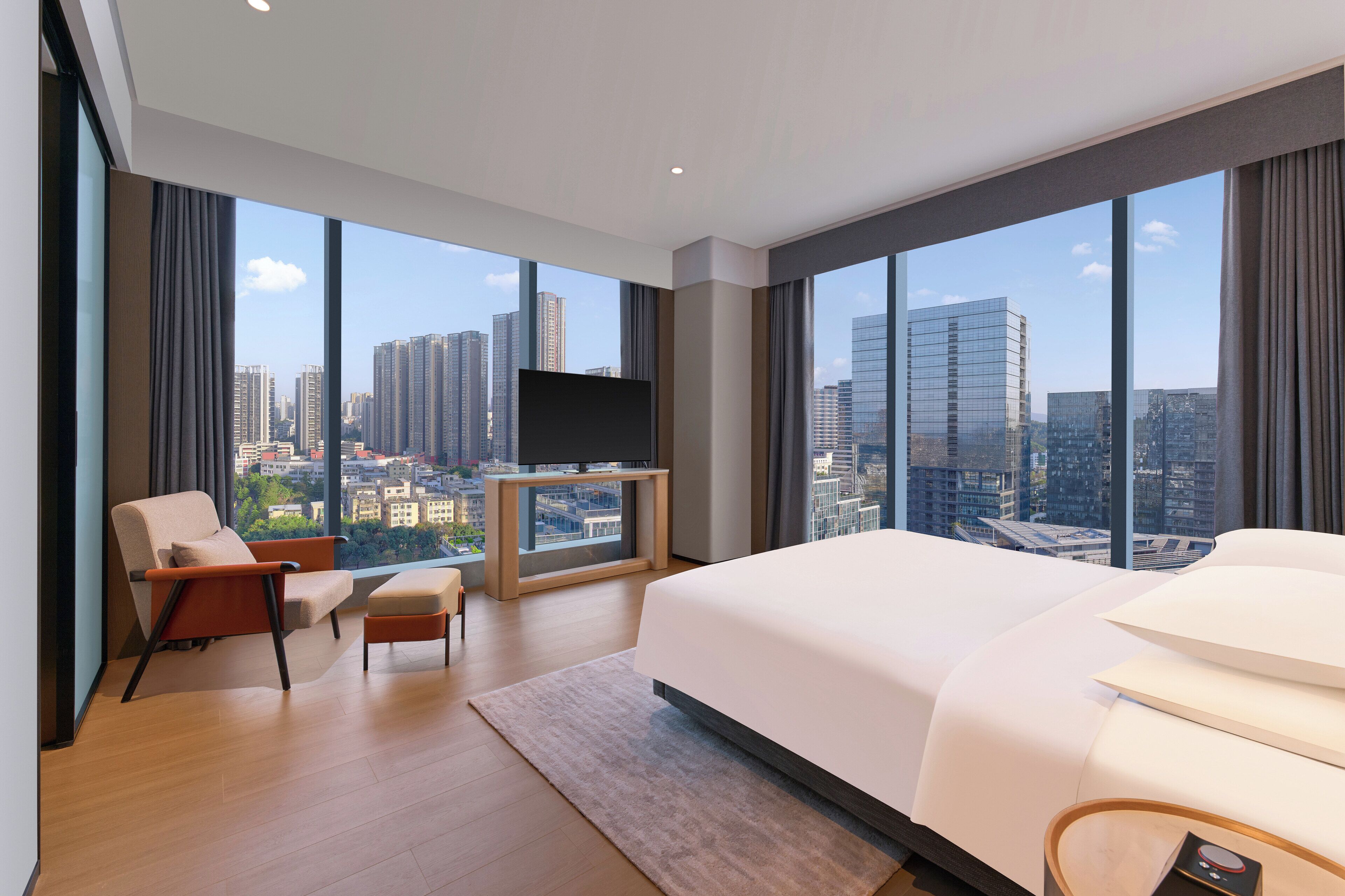Una habitación de hotel moderna con una cama grande, televisión y vistas a la ciudad.