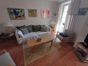 En stue med sofa, sofabord, stol, lampe og billedkunst på væggen.