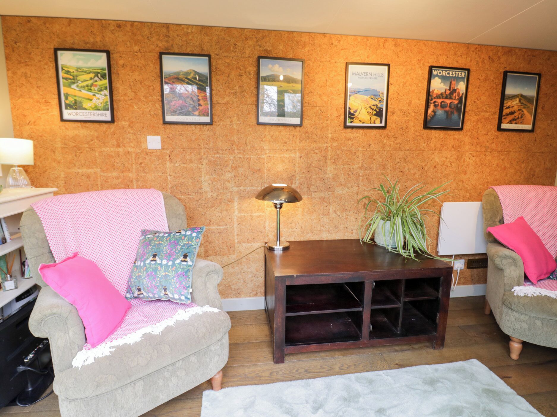 A living room with two armchairs, a coffee table, and a lamp. There are framed pictures on the wall and a plant on the table.