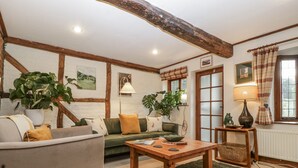 A cozy living room with a green sofa, a wooden coffee table, and a large plant. - Magpie Cottage (Worcester)