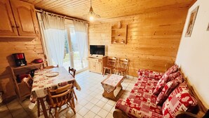 Una habitación acogedora de estilo cabaña con comedor, sofá, televisor y chimenea.