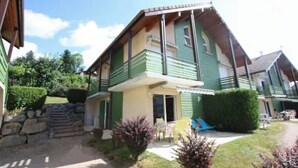 Una casa de dos pisos con un balcón, una puerta principal y un pequeño jardín con un camino.