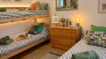 A room with bunk beds, a dresser, a mirror, and a small table with a lamp.