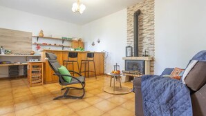 A cozy living room with a fireplace, a dining area with a bar, and a kitchen with wooden shelves. - Ursula's Cozy Retreat in Santa Ursula (Santa Ursula)