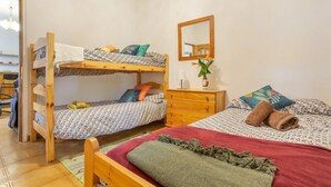 A dormitory room with bunk beds, a dresser, a mirror, and a small table. - Ursula's Cozy Retreat in Santa Ursula (Santa Ursula)