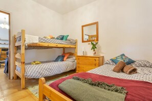Ein Schlafsaalzimmer mit Stockbetten, einem Schrank, einem Spiegel und einem kleinen Tisch.