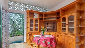 Una zona de comedor con un aparador de madera, una mesa con mantel rojo y sillas.