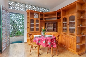 A dining area with a wooden cabinet, a table with a red tablecloth, and chairs. - Ursula's Cozy Retreat in Santa Ursula (Santa Ursula)