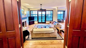 Un salón amplio con chimenea, televisión y un ventanal con vistas al exterior.