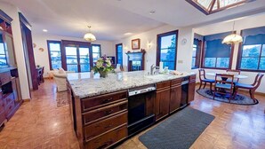 Una cocina amplia con una isla grande, armarios de madera y vistas al exterior a través de ventanas grandes.