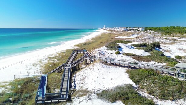 A coastal walkway leading to a beach with a clear view of the ocean and a distant lighthouse. - Prominence Salt & Light - 6 Seat Golf Cart Included (Walton County)