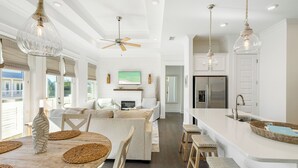 A modern kitchen with a large island, white cabinetry, and a stainless steel refrigerator. - Prominence Salt & Light - 6 Seat Golf Cart Included (Walton County)